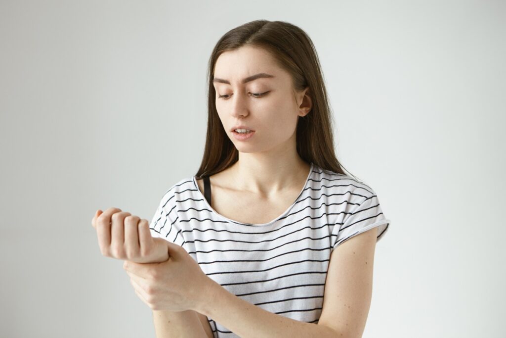 Mulher observando suas unhas, simbolizando a preocupação com manchas brancas que podem indicar problemas de saúde.