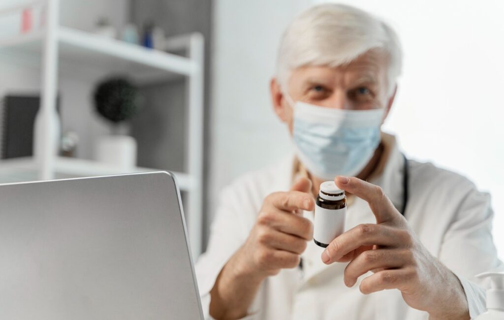 Médico mostrando frasco de medicamento para tratamento de câncer infantil, com o uso do Betadinutuximabe (Qarziba) pelo SUS.