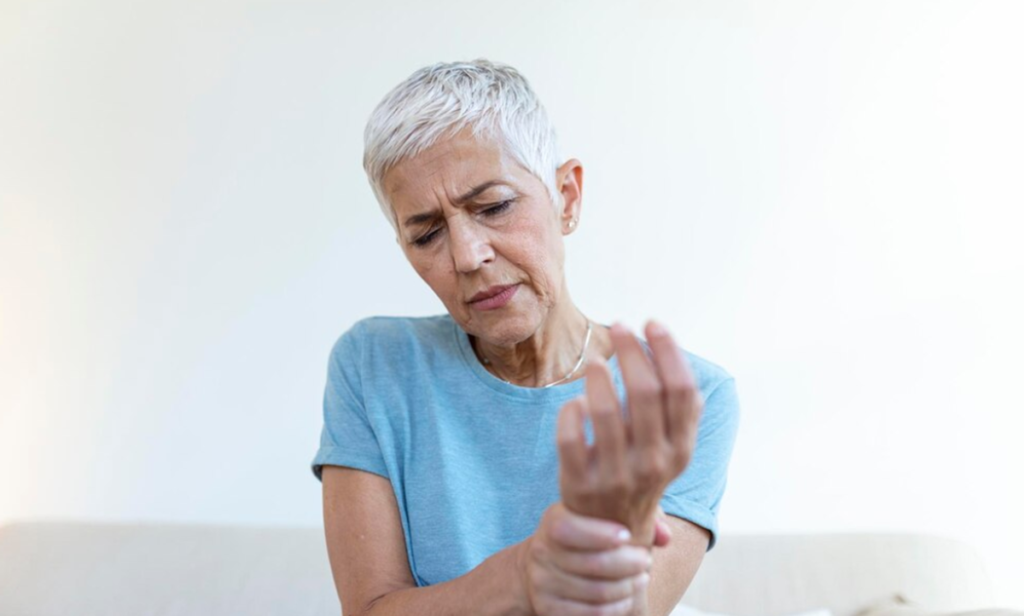 Senhora segurando o pulso com expressão de incômodo