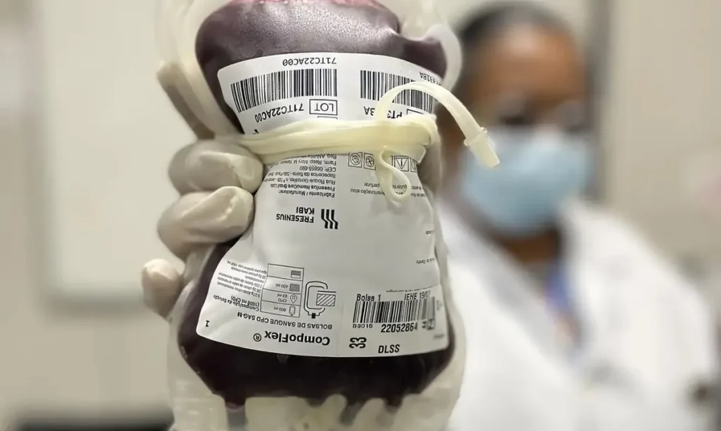 Profissional de saúde segurando uma bolsa de sangue, simbolizando avanços no tratamento de doenças sanguíneas raras.