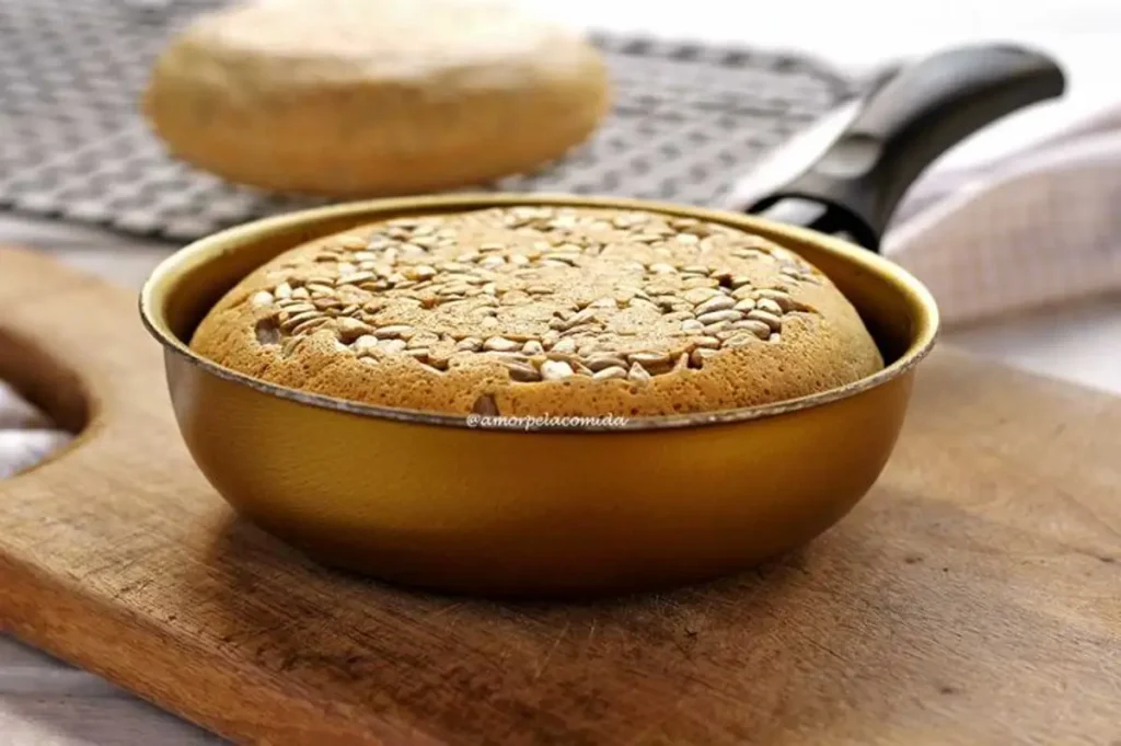 Pão de aveia sendo preparado na frigideira, com sementes por cima.