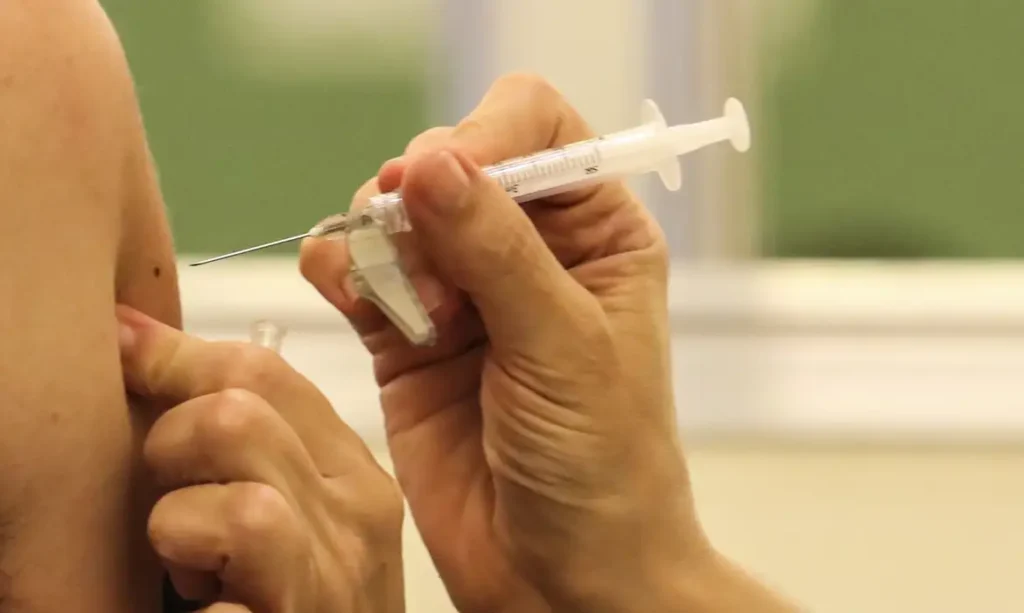 Vacina da Gripe entra no Calendário Nacional de Vacinação: Veja quem deve tomar e quando estará disponível 1 Aplicação de vacina no braço de uma pessoa, representando a imunização contra a gripe.