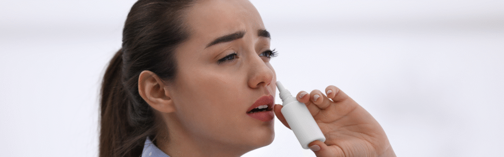 Mulher usando descongestionante nasal, aplicando spray nas narinas.